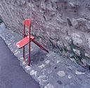 Red Folding Chair Leaning Against Stone Wall